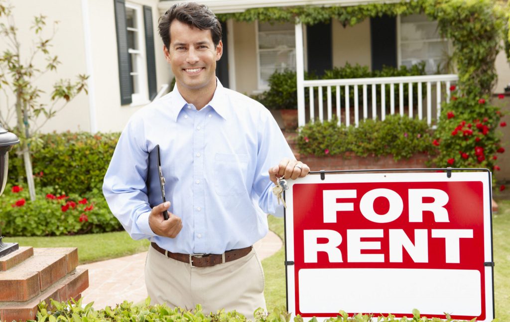man standing by for rent sign