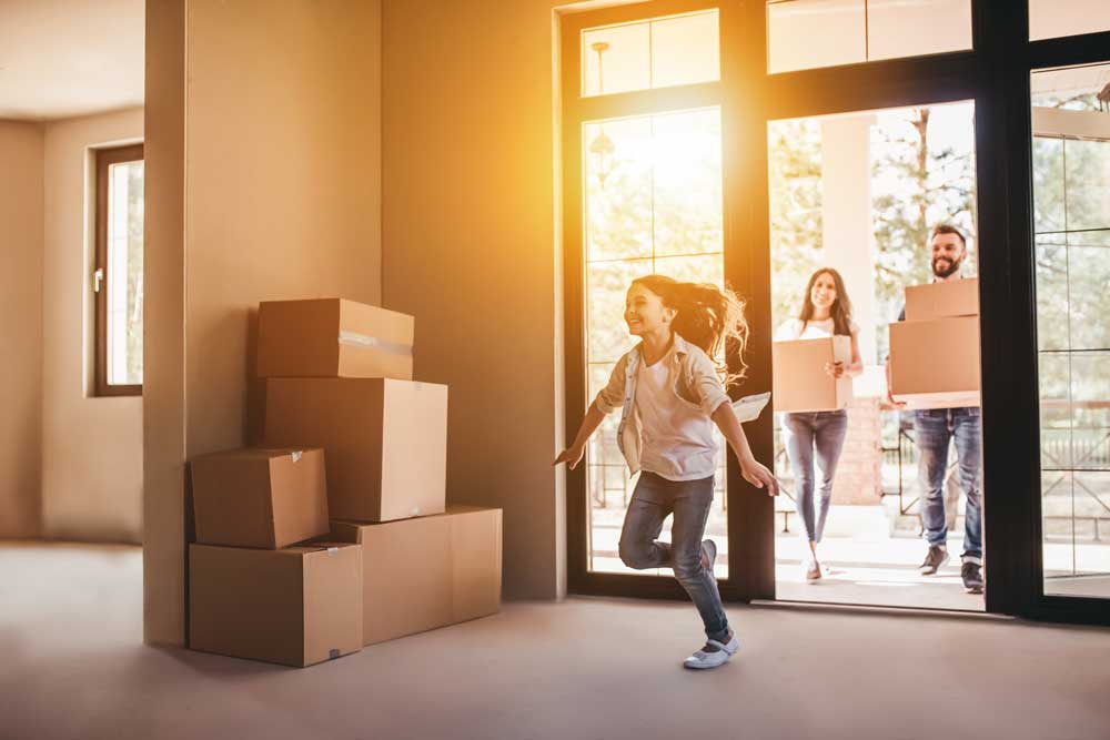Young family entering newly-purchased home with boxes