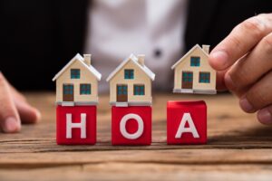 wooden home figurines on top of HOA letters