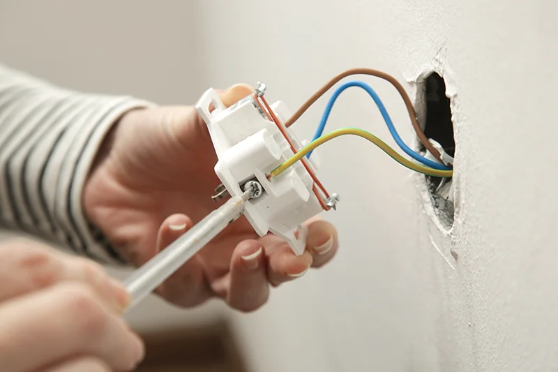 Someone repairing an electrical outlet.