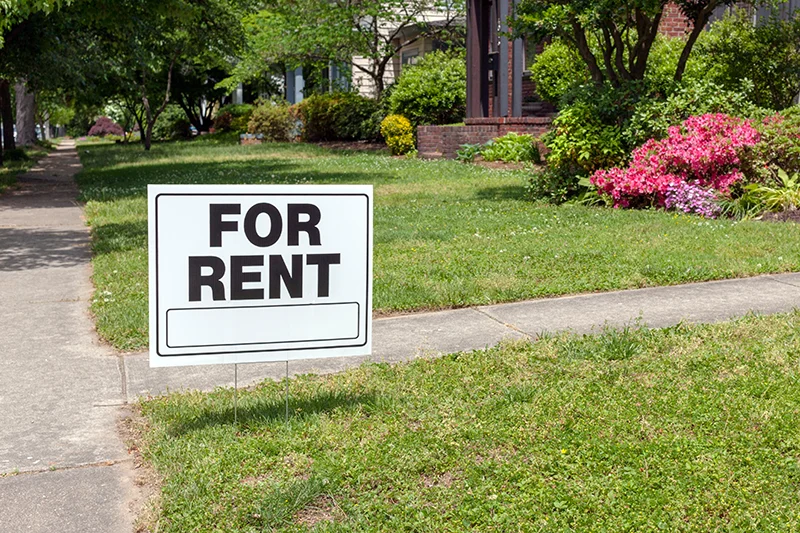 For rent sign and flowers in house garden