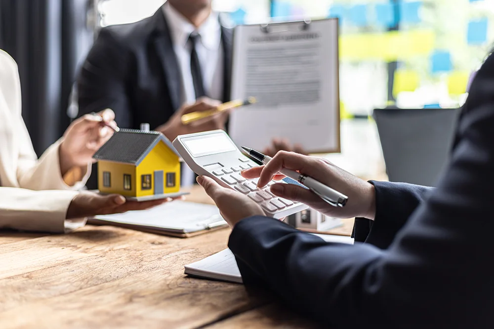 Three people gathered around a table going over paperwork.