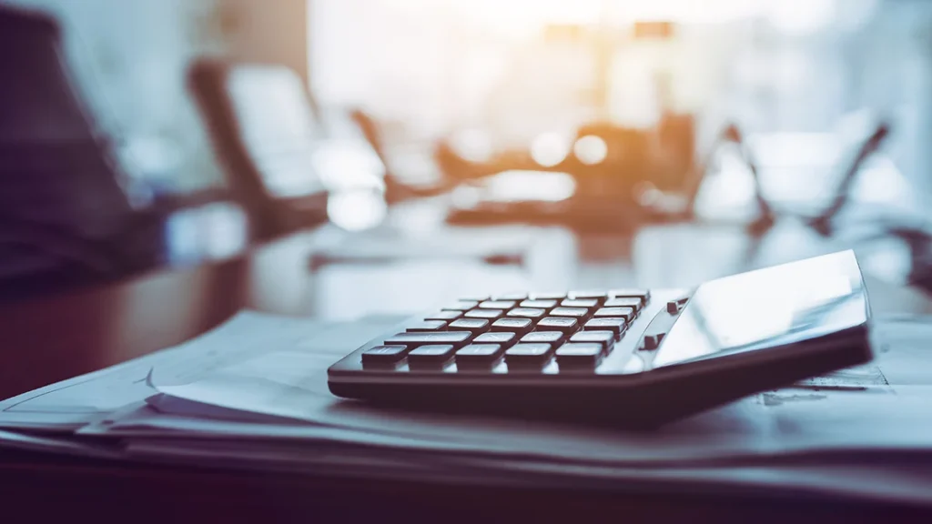 Calculator on a desk with papers.