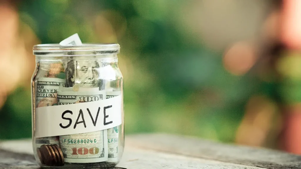 Money in a glass jar labeled "save."
