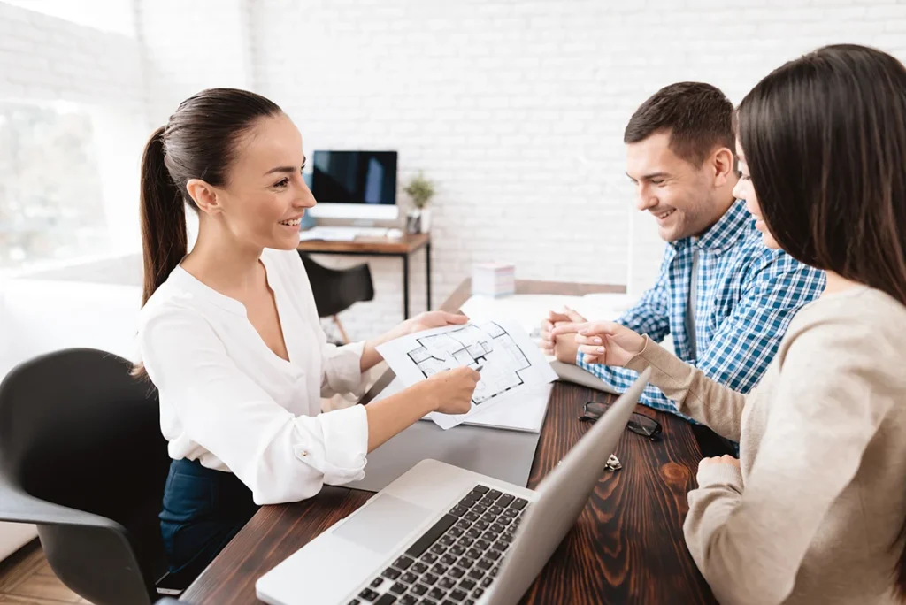 A professional property manager meeting with a couple, looking over a floorplan.