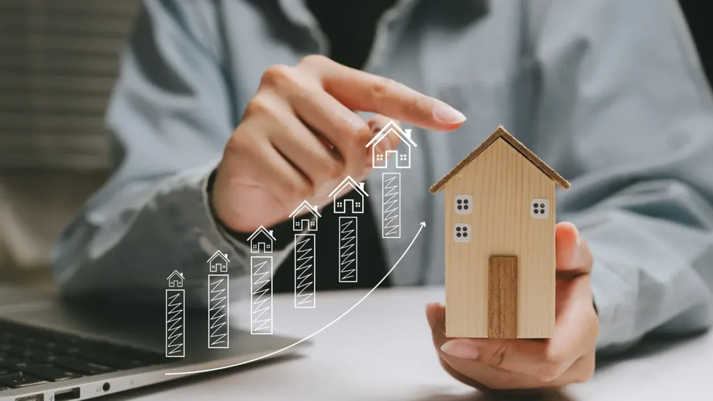 Person using their finger to trace an imaginary line of sketched houses to the rooftop of small wooden home in their opposite hand.