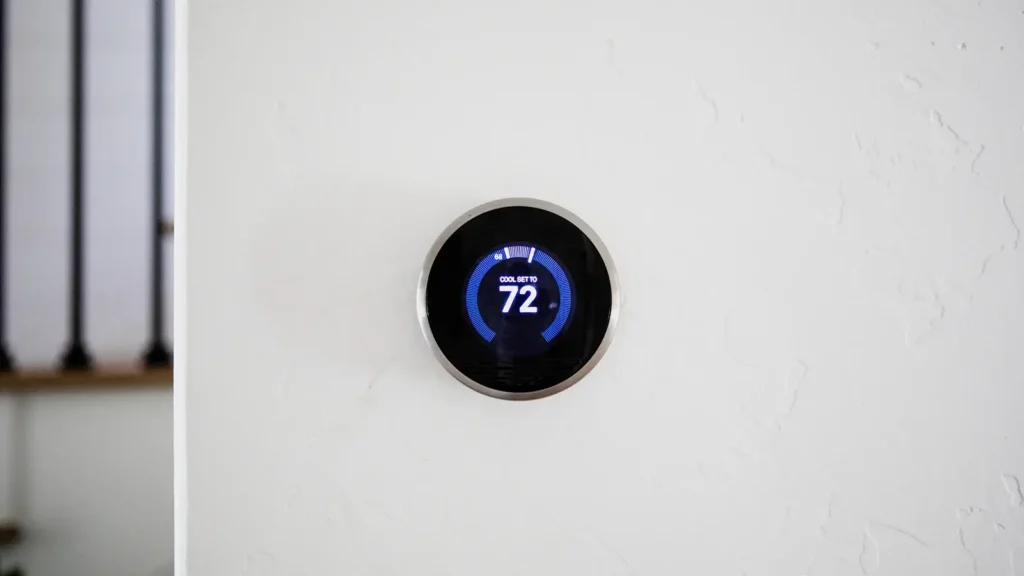Circular smart thermostat pictured on the wall of a home.