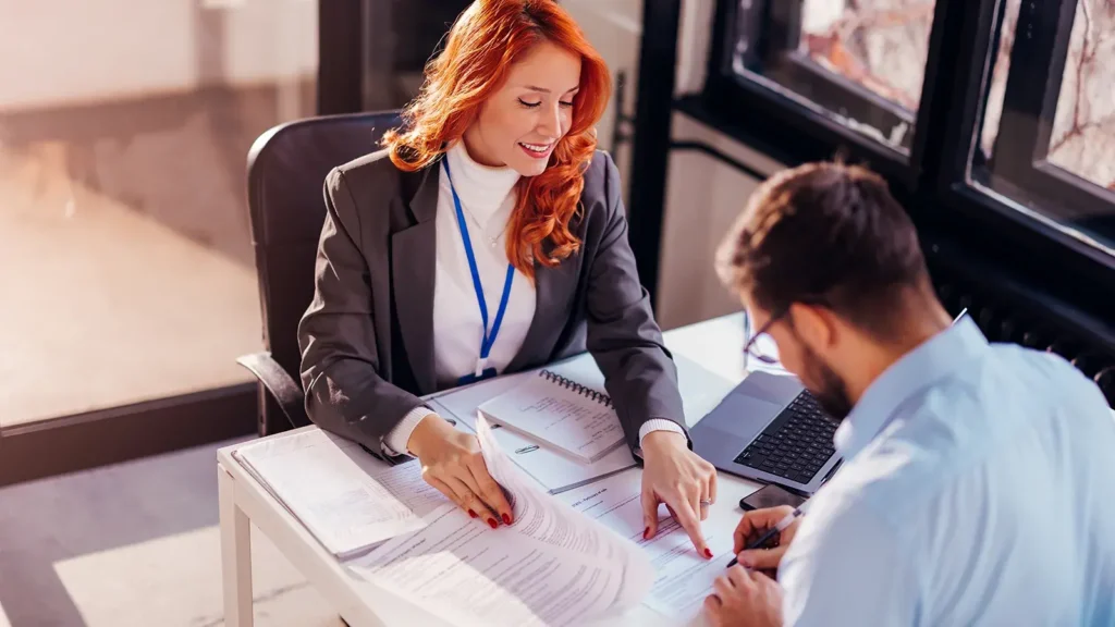 Female property manager going over paperwork at a desk with a male renter.