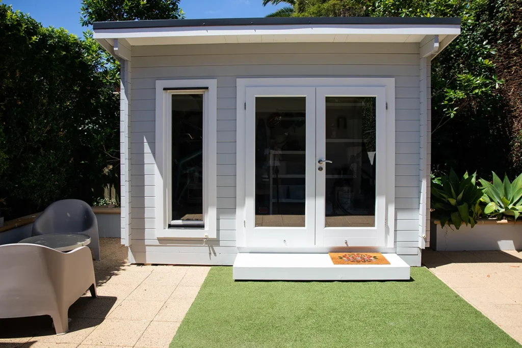 accessory dwelling unit with glass doors, small porch, and green yard.