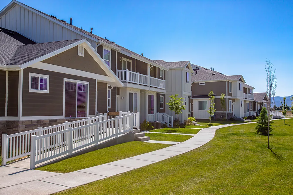Row of rental homes in a neighborhood with a sidewalk and green lawn out front